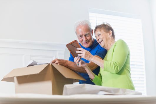 Couple holding frame in front of box
