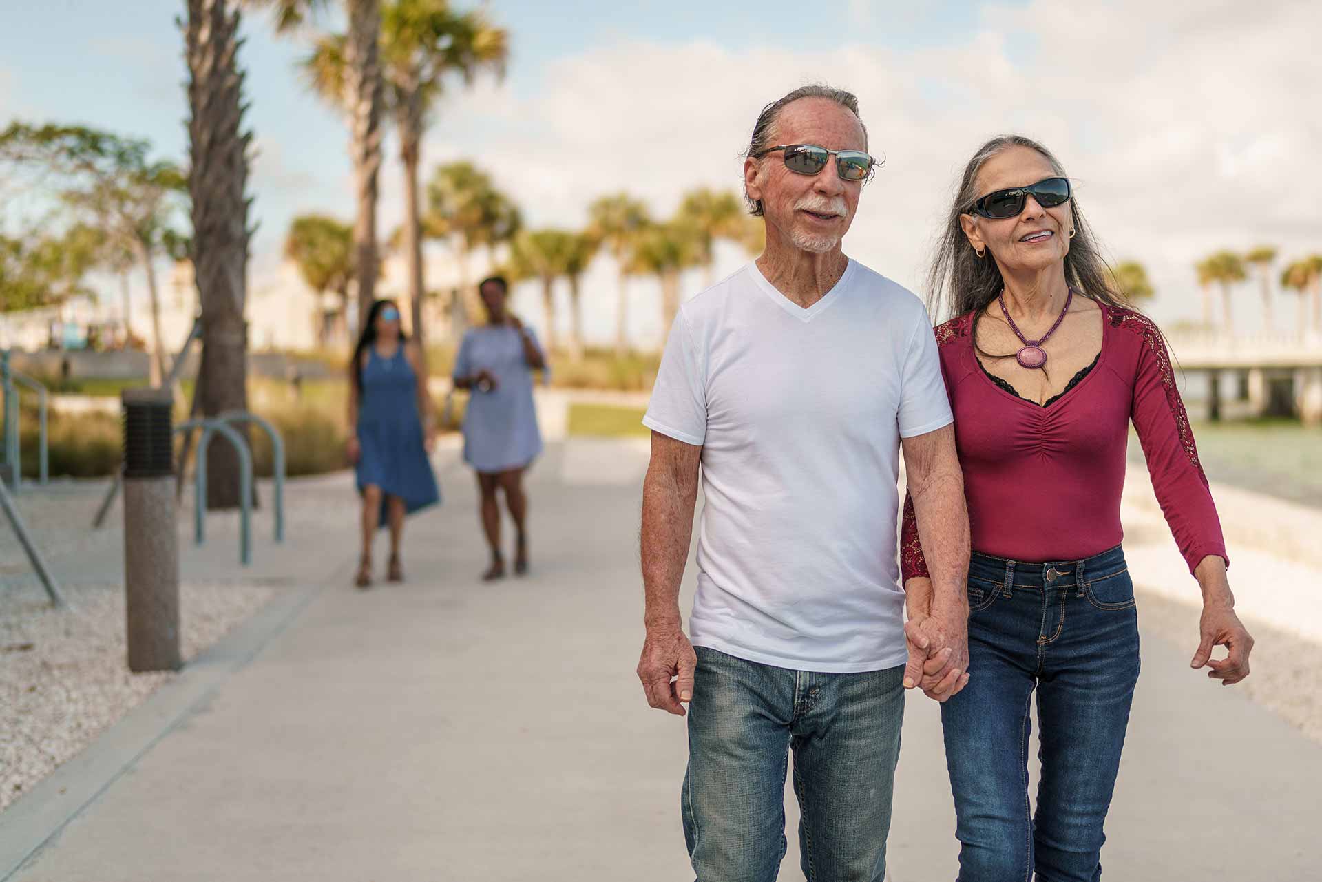 Two older adults are walking hand in hand