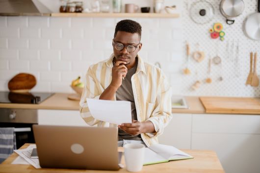 Man holding paper with table and laptop