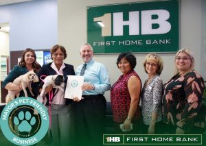 First Home Bank group photo with dogs and employees and Mayor's Pet-Friendly Business logo